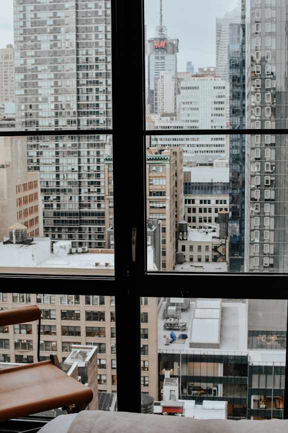 A cityscape is visible through a window with a chair in the foreground.