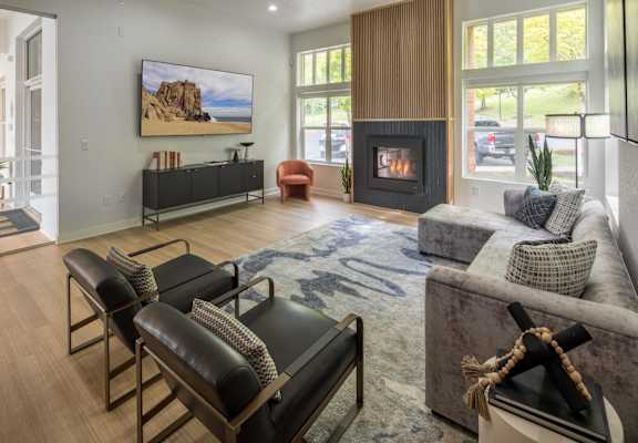 A living room with a fireplace and a painting of a beach scene on the wall.