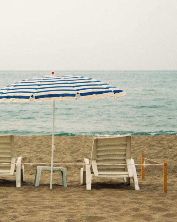two beach chairs and an umbrella on the beach