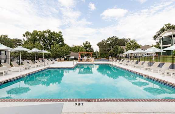 A large outdoor swimming pool with lounge chairs and umbrellas.