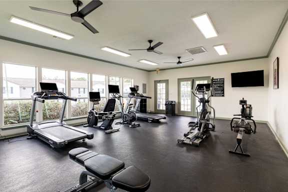 A spacious gym with a variety of equipment including treadmills, exercise bikes, and weight machines.