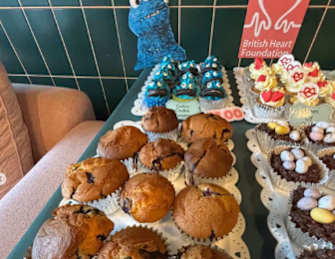 A table full of assorted baked goods with a sign for the British Heart Foundation in the background.