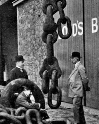 Three men are standing in front of a wall with a sign that says "D's B".