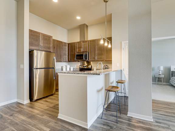 a kitchen with stainless steel appliances and a bar with stools