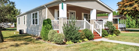 a small house with a porch and a lawn in front of it