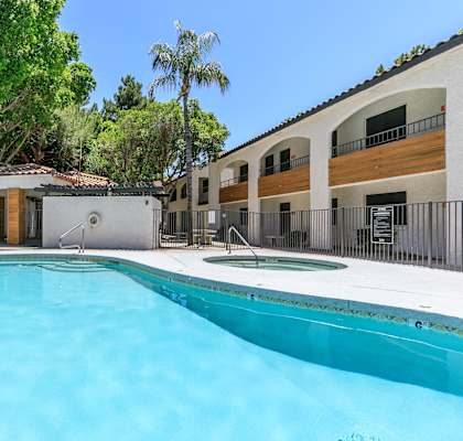 A swimming pool in front of a building with a fence around it.