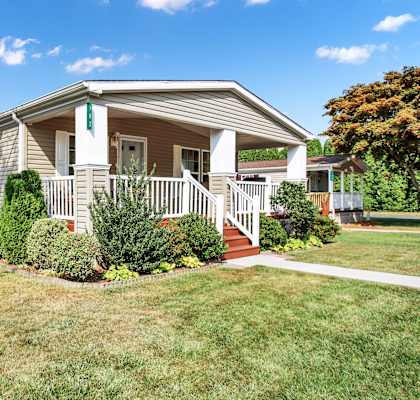 a small house with a porch and a lawn in front of it