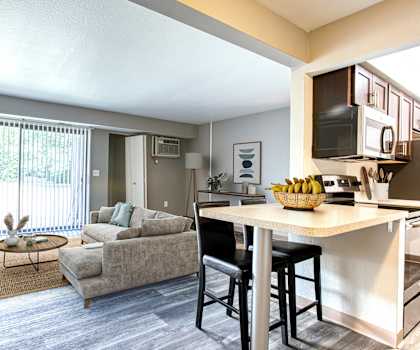 A modern kitchen with a dining table and chairs is adjacent to a living room with a couch and a coffee table.