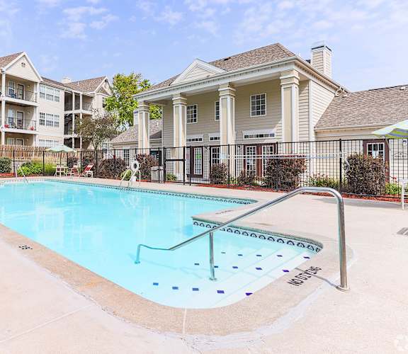 A swimming pool in front of a building with a white fence around it.