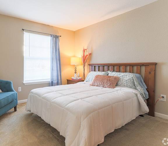 A bedroom with a white bed and a blue chair.