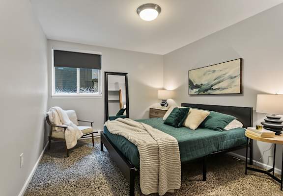 a bedroom with a bed and a chair and a window