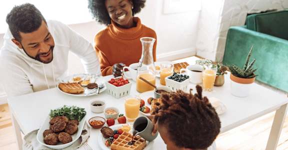 a family sitting at a table eating food at a dining table