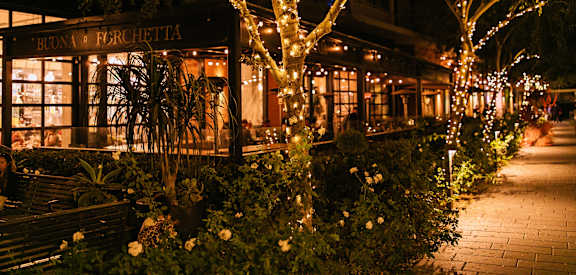A restaurant named Buona Ferretti is lit up at night with lights and decorations.