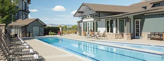 a swimming pool with chairs around it in front of a house