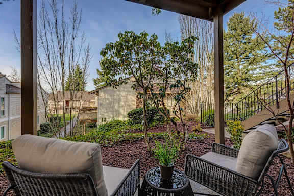 a patio with two chairs and a table with a potted plant on it