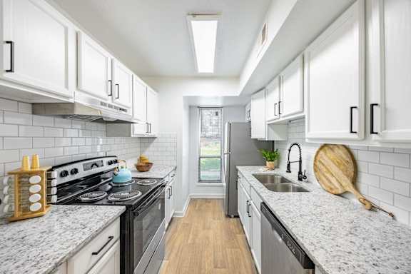 a kitchen with white cabinets and a stove and a sink
