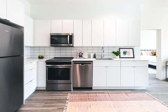 a white kitchen with stainless steel appliances and white cabinets