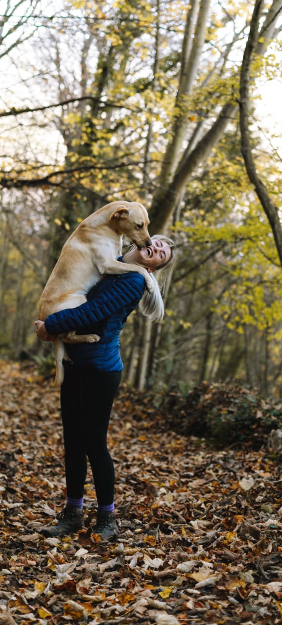 a woman holding a dog in the woods