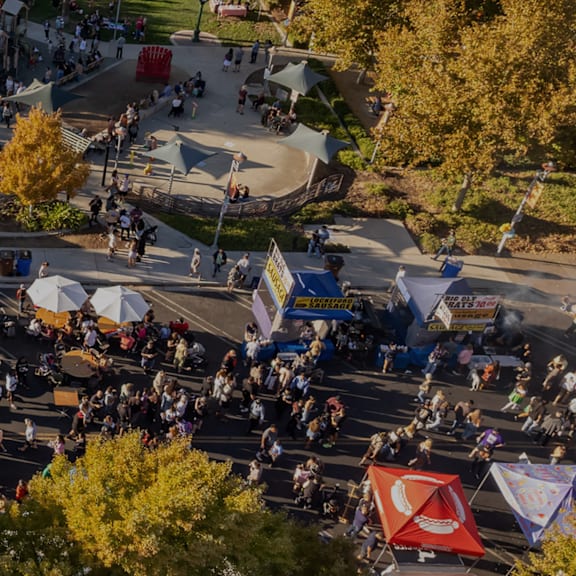 A busy outdoor market with many people walking around.
