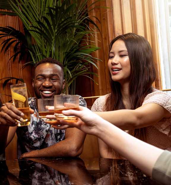 Two people toasting with drinks at a table.