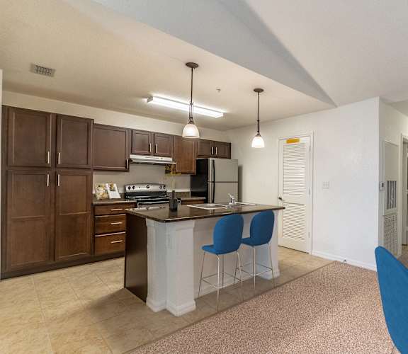 a kitchen with an island and a dining table with blue chairs