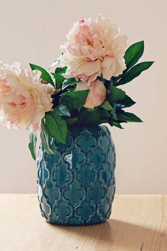 A blue vase with flowers on a wooden table.