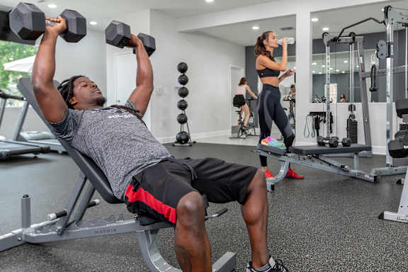 A man and a woman are working out in a gym.