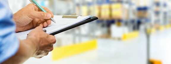 Person checking warehouse inventory holding clipboard