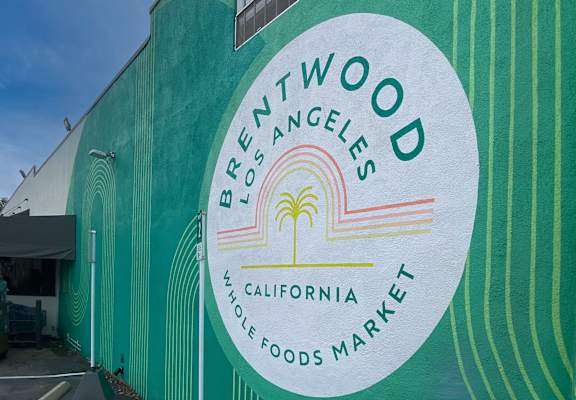 A green building with a sign that says Brentwood Los Angeles Whole Foods Market.