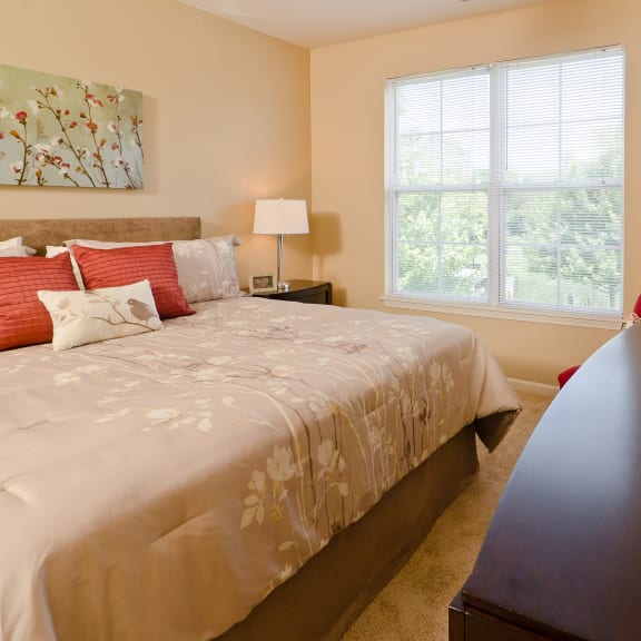 a bedroom with a large bed and a dresser with a vase of red flowers on