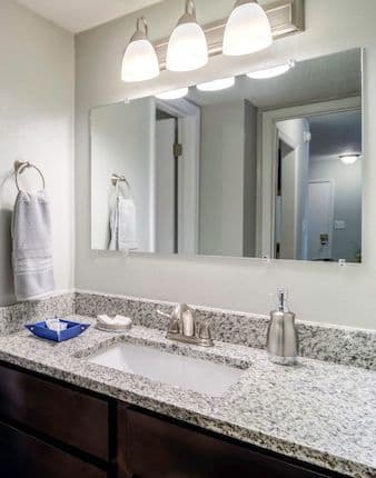 Bathroom with large quartz sink vanity, mirror, and light kit