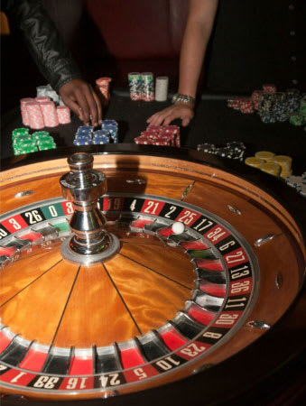A person is playing with a roulette wheel in a casino.