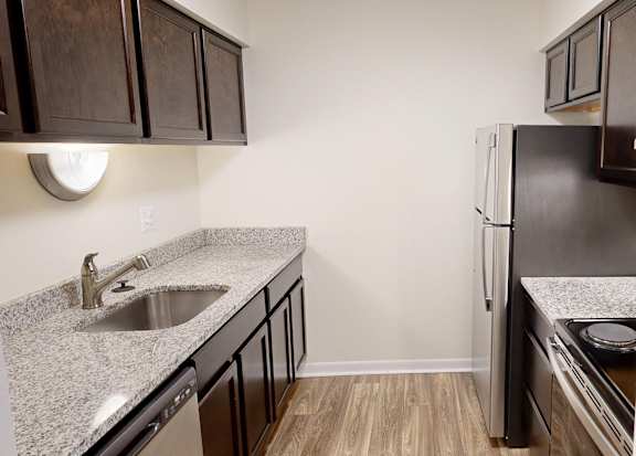 A kitchen with a black fridge and brown cabinets.