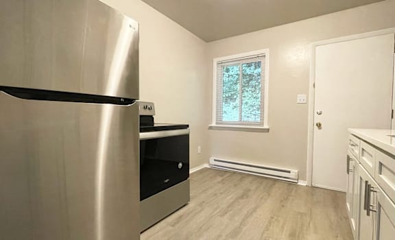 A kitchen with a stainless steel refrigerator and wooden flooring.
