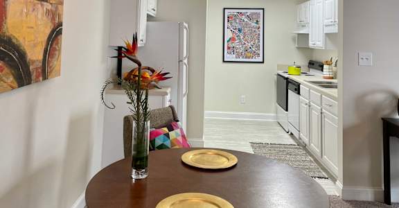 a dining area with a table and chairs and a kitchen in the background