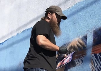 Artist Shane of Mammoth Murals & Signs painting a mural outside at The Citizen Birmingham