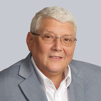 a portrait of a man with glasses and a gray suit