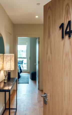 a wooden door with the number 14 on it and a table with a lamp and a mirror