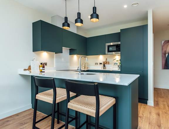 a kitchen with green cabinets and a blue island with two stools
