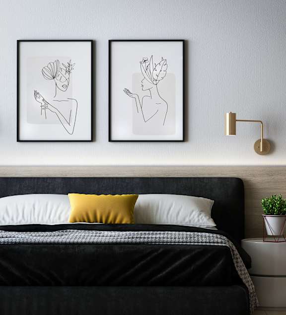 a bedroom with a bed and two paintings on the wall
