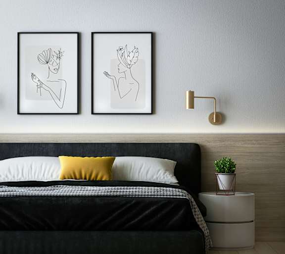 A bedroom with a black bed and two framed artworks on the wall.