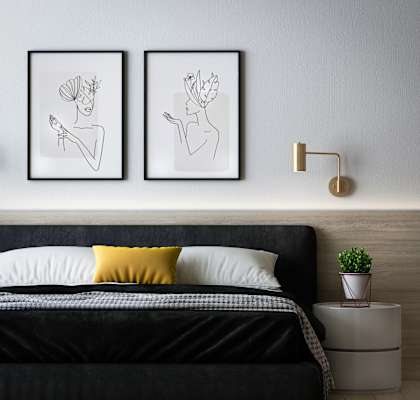 a bedroom with a bed and two paintings on the wall