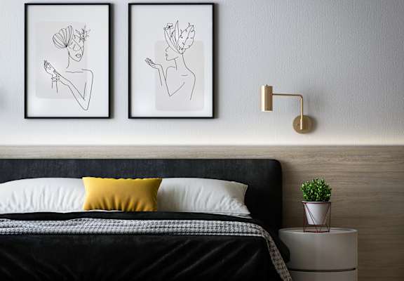 a bedroom with a bed and two paintings on the wall