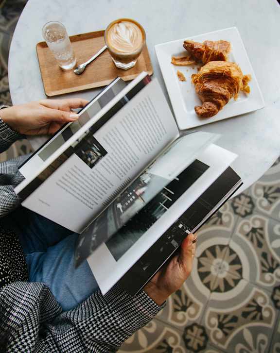 A person is reading a magazine while having a meal.