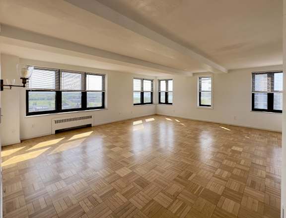 the living room of an empty apartment with wood flooring and windows
