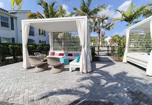 a patio with two chairs and a table under a canopy at The Crest at Laurel Canyon Apartments, Naples, Florida
