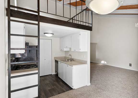 A kitchen with white cabinets and a black metal staircase.