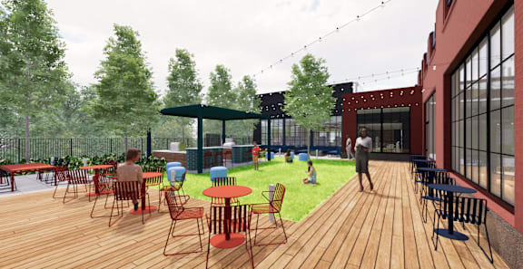 A wooden deck with tables and chairs is surrounded by trees. at University Commons in Pittsburgh, PA