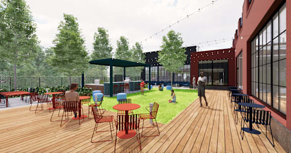 A wooden deck with tables and chairs is surrounded by trees. at University Commons in Pittsburgh, PA