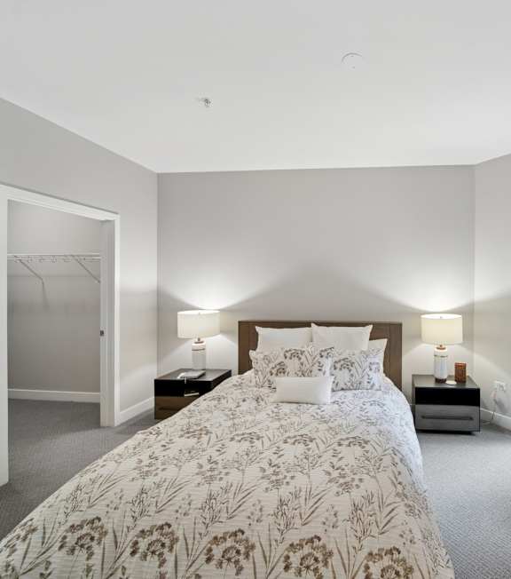 A bedroom with a bed, nightstands, and two wall lamps.